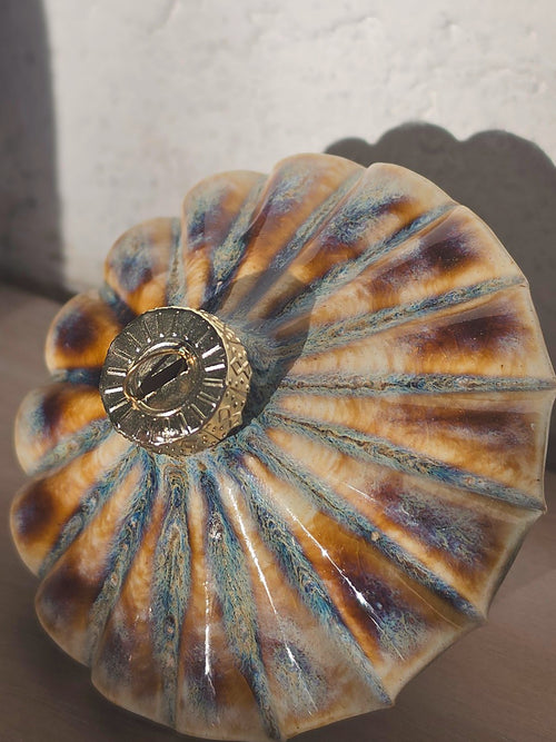 Close top-down view of the Amber Blue Ribbed Diamond ceramic bauble, amber glaze streaked with blue and plum along every ridge around the gold cap.