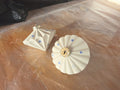 Two white ceramic Ribbed Diamond baubles with hand drawn blue stars, one upright and one seen from above.